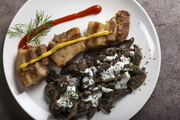 Pieces of fried fat pork meat with mushrooms and sour cream