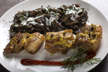 Close up of pieces of fried fat pork meat with mushrooms and sour cream