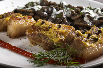 Close up of pieces of fried fat pork meat with mushrooms and sour cream