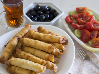 turkish cigarette patty on white plate with olive and tomato