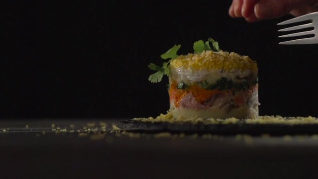 The hand decorates the mimosa salad with herbs.