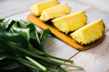 Sliced fresh pineapple on a wooden background in sunlight