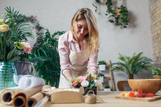 Portrait of florist composing bouquet at table on background of flowers