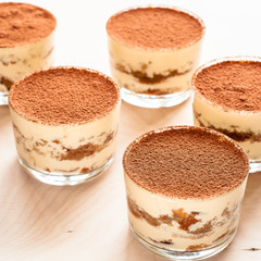 Homemade tiramisu, traditional Italian dessert in glass on wooden table