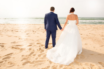 Fototapeta na wymiar bride and groom on the beach Just married couple on fence