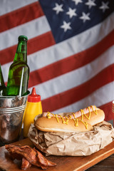 classic American hot dogs with mustard. next to fried bacon and a bottle of beer