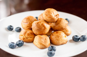 Homemade profiteroles served with blueberries on a white plate