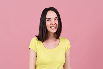 a friendly cheerful brunette girl smiles widely with a snow-white smile and looks expressively at the camera. 