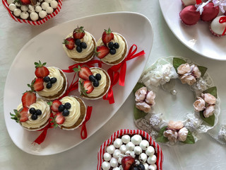 Various sweet delicious desserts: cakes and cup cakes on the wedding table. View directly above. Decorated in red and white color scheme