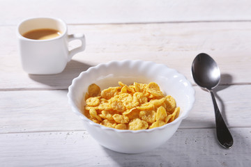Corn Flakes cereal with milk in a bowl and cap with espresso coffee. Morning breakfast.