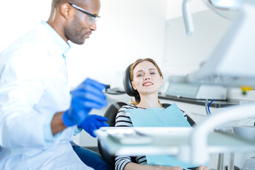 Obraz premium Nice patient. The focus being on a pretty cheerful young woman sitting in a dentist chair and smiling at the camera while waiting for an oral cavity checkup