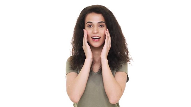 Portrait of happy hispanic woman 20s emotionally reacting and grabbing her face after listening surprising news, over white background