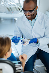 Good teacher. The top view of a handsome young dentist holding a dental model and using a...