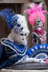 Fototapeta na wymiar Women in costume with fans and ornate painted feathered masks at Venice Carnival. 