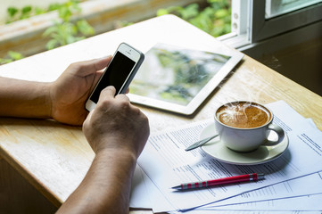 Asian man is using smart mobile phone and drinking coffee.