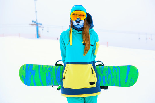 Beautiful young snowboarder girl holding snowboard.