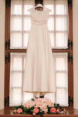 Beautiful White Wedding Gown Hanging by Window