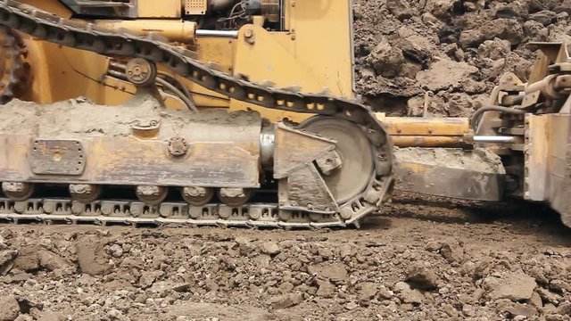 Heavy earthmover, bulldozer machine is leveling construction site
View on bulldozer, crawler while he is moving and leveling ground at building site. 
