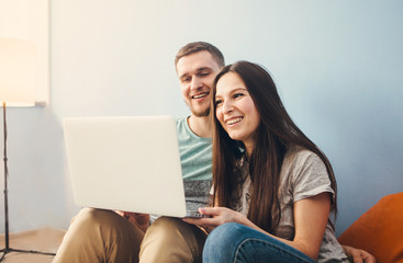 Fototapeta premium Young couple sitting at home and using laptop, surf the Internet.