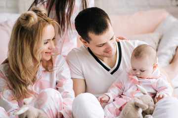 Smiling young parents and their two children are very happy, they are at home on the bright interior