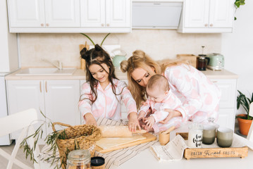 Happy loving family are preparing bakery together. Mother and two daughter girl are cooking cookies and having fun in the kitchen. Homemade food and little helper.