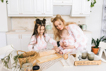 Happy loving family are preparing bakery together. Mother and two daughter girl are cooking cookies and having fun in the kitchen. Homemade food and little helper.