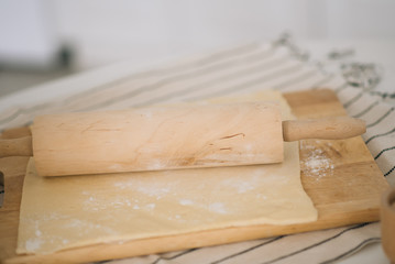 The process of preparing the dough on a wooden Board with sweet flour in the white kitchen, selective focus