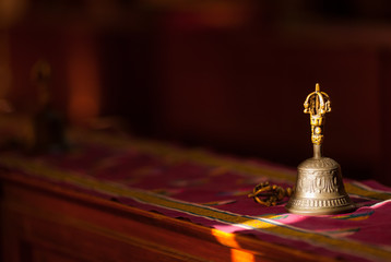 Ritual hand bell in the Buddhist temple as the enlightenment symbol, has got to a sunlight beam. - obrazy, fototapety, plakaty