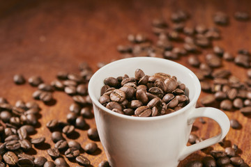 Coffee beans in a cup on a dark wooden background