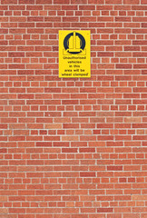 Fototapeta na wymiar A closeup of brickwork with a warning sign.