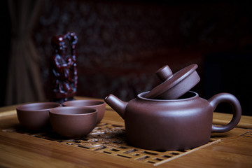 Clay tea set stands on a wooden board.