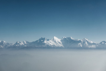 Fototapeta na wymiar The Himalayas as seen from an airplane in Nepal. Layer of clouds beneath the mountain tops. 