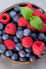 Juicy and fresh blueberries with green mint on rustic gray table.