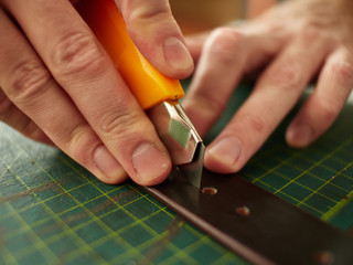 The tanner cuts through the leather belt a hole for the tongue of the buckle.