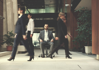 business man sitting in office chair, people group  passing by