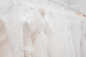 Fototapeta na wymiar Wedding dresses for bride on hangers against white background loft store. Concept wedding, engagement, attributes, clothing, love.