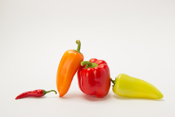 Several ripe sweet and hot peppers of red and orange on a white background