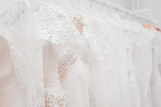 Wedding dresses for bride on hangers against white background loft store. Concept wedding, engagement, attributes, clothing, love.