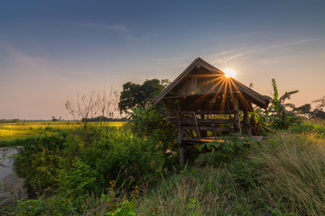 Old cottage in field at sunset