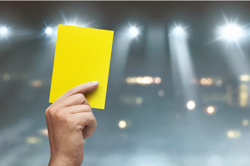 Hand of referee with yellow card