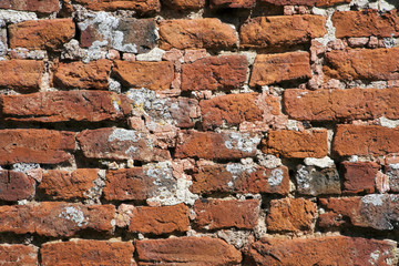 Very old weathered, damaged, badly repaired hand made red brick wall close up