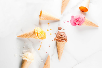 Homemade chocolate, vanilla, berry ice cream in ice cream cones, white marble background copy space top view