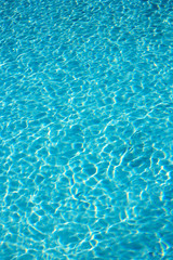 Textured light effect on the surface ripples of a blue outdoor swimming pool. Full frame background texture.