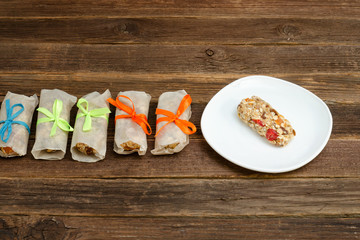 Bars of muesli in a package on a wooden table. Bar with a raspberry on a saucer