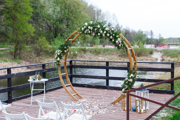 Area of the wedding ceremony in forest, near river on the pier.