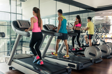 Fototapeta na wymiar Full length rear view of a fit active woman running on treadmill during high-intensity cardio session in a trendy fitness club with modern equipment
