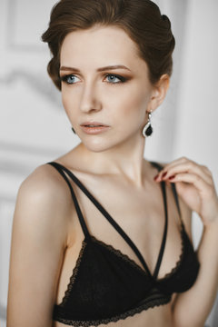 Beautiful, sensual and fashionable young woman in black lingerie and earrings