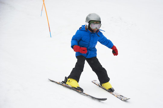 Child boy skiing in the mountains on snowy winter day. Kids in winter sport school in resort. Family fun in the snow. Skier learning and exercising on a slope.