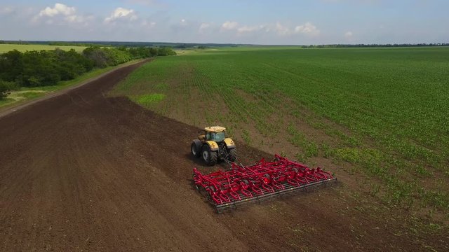 Aerial drone tracking shot of tractor seeding, sowing agricultural crops in a field. View from above