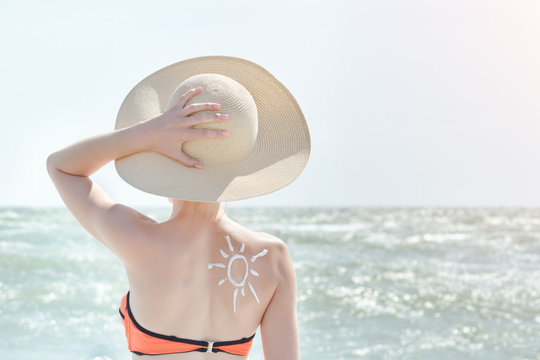 Girl in a hat against sea. On the back is painted sun